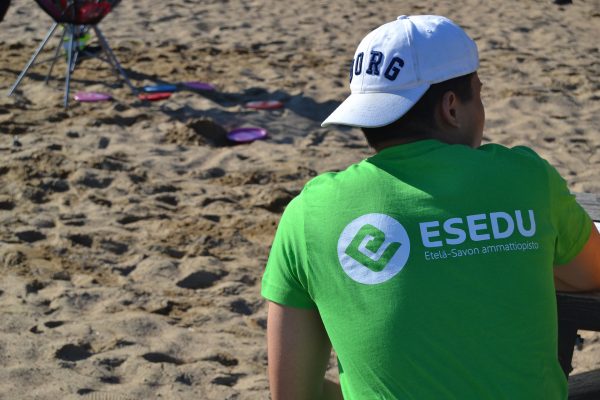Esedun opiskelija firsbeegolfkorin edessä rannalla