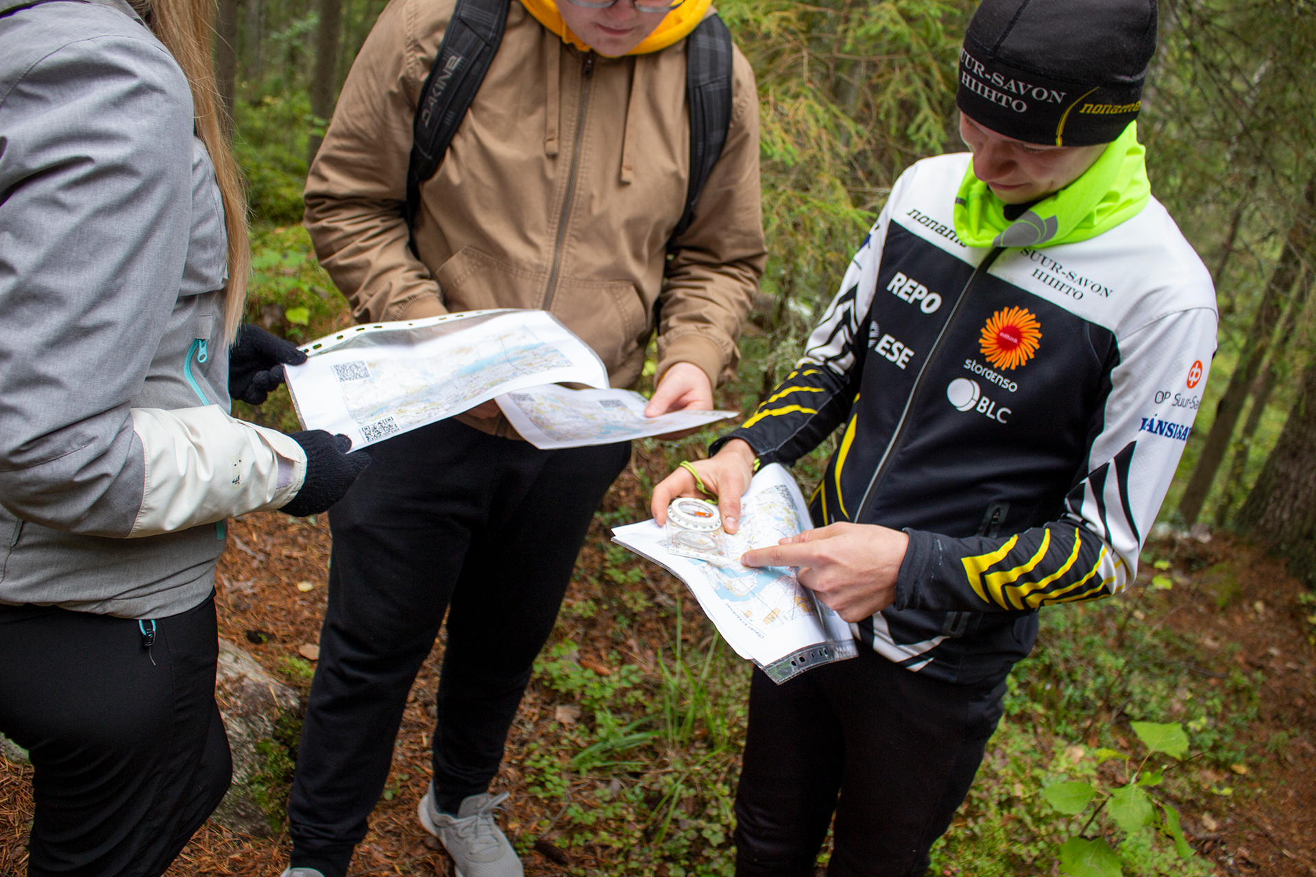 Opiskelijat suunnistamassa metsässä, kompassin ja kartan tarkistusta oikeasta suunnistusreitistä