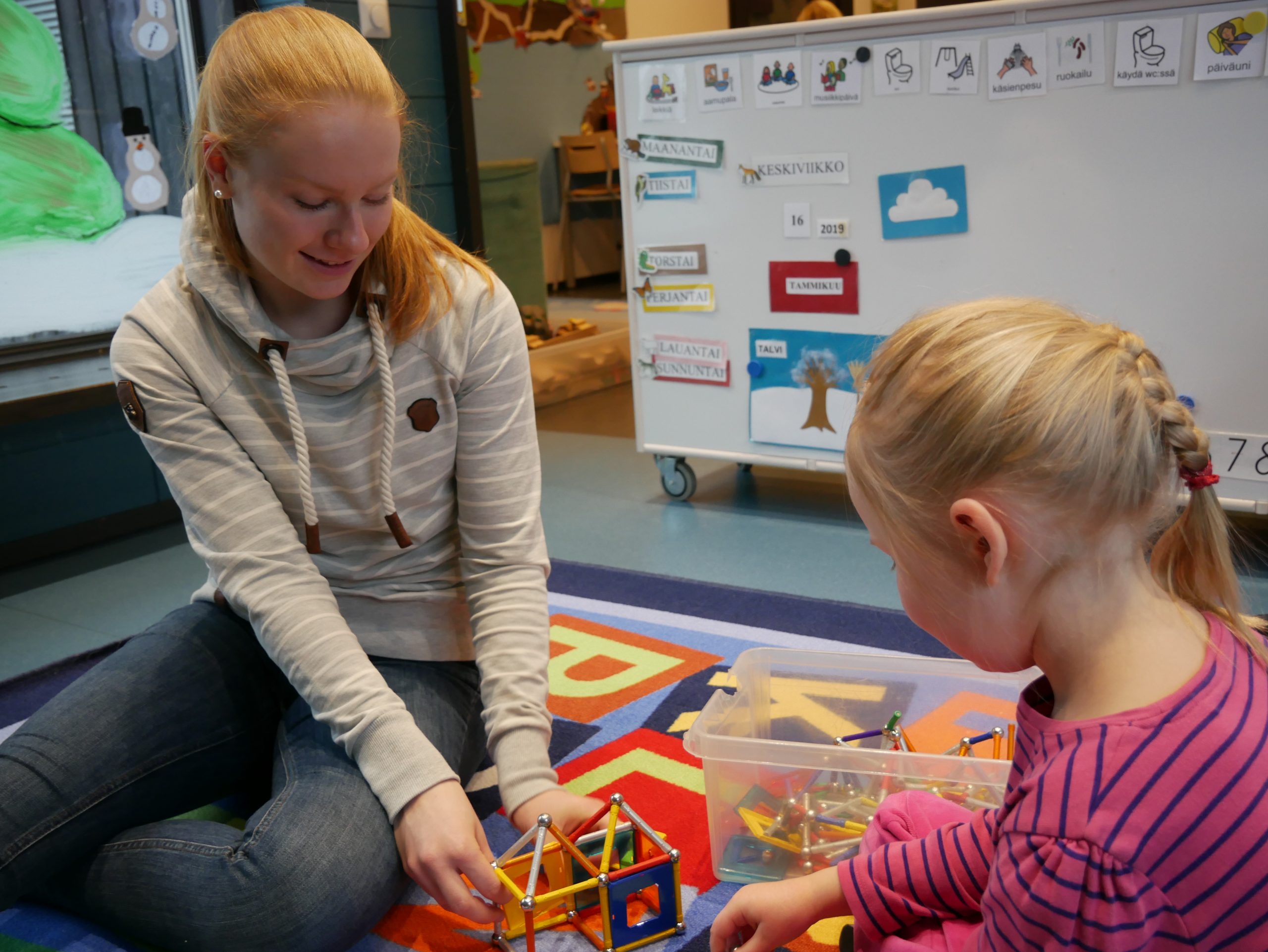 Lähihoitaja opiskelija leikkimässä lapsen kanssa magneettileluilla