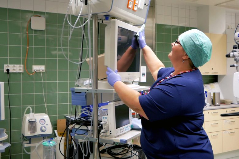Terveydenhuoltotilojen siistijä puhdistamassa sairaalan laitteita ja monitoreja.