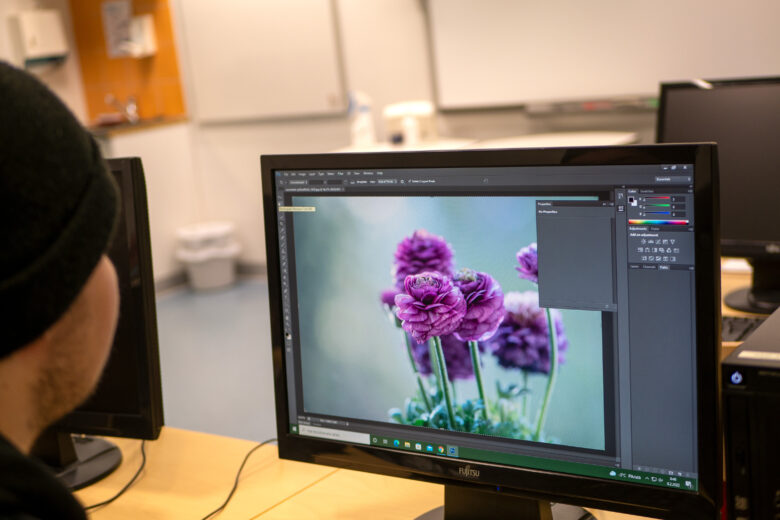 Opiskelija tekee kuvankäsittelyä tietokoneella kukkakuviosta.