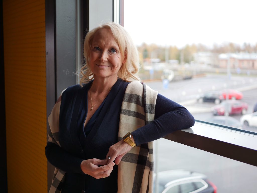 Nainen nojaa yhdellä kädellä kaiteeseen