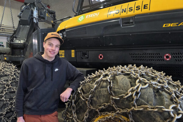 Mies nojaa metsäkoneen renkaaseen