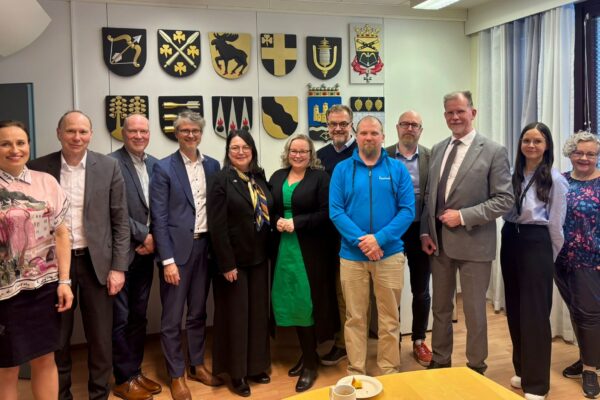 Joukko ihmisiä seisoo rivissä ja katsoo hymyillen kameraan